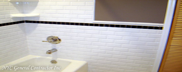 Bathtub area with subway style tiles along with navy blue tiles bordering the entire bathroom... General Contractor